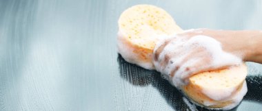 İnsanlar elleri sarı sünger ve köpük temizleyici ile araba yıkamak için el ele tutuşuyorlar. Konsept araba yıkama. İleti yazmak için yer bırakın. 