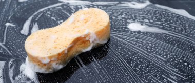 Sarı sünger ve sabun arabayı yıkamak için. Motor kaputu temizleniyor. Konsept araba yıkama. İleti yazmak için yer bırakın.