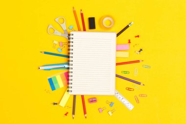 Eğitim anlayışı üst görünüm notlar ve aksesuar kırtasiyesi okuldaki sarı arka planda kütüphanede öğrenim görüyor.