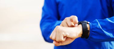 Bilek saatini kontrol eden sporcu dışarıda antrenman yapmaya hazır..