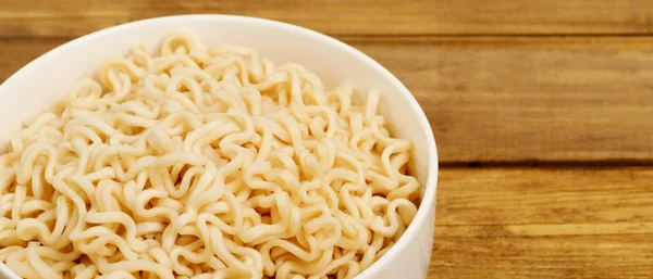 The instant noodles were placed in a white cup on the dining table.