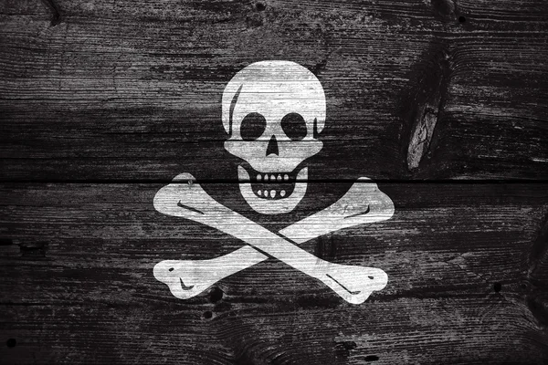 Traditionella Jolly Roger piratkopiering flagga, målade på gammal trä planka bakgrund — Stockfoto