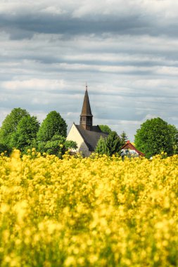 WROCLAW, POLAND - 24 Mayıs 2021: Gogolow 'daki St. Martin Kilisesi Sleza Dağı eteklerinde, çiçek açan tecavüz tarlalarıyla çevrili.
