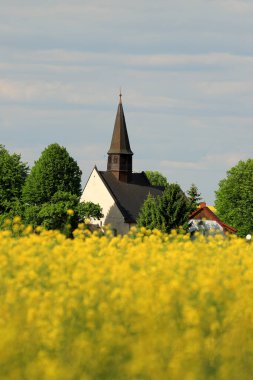 WROCLAW, POLAND - 24 Mayıs 2021: Gogolow 'daki St. Martin Kilisesi Sleza Dağı eteklerinde, çiçek açan tecavüz tarlalarıyla çevrili.