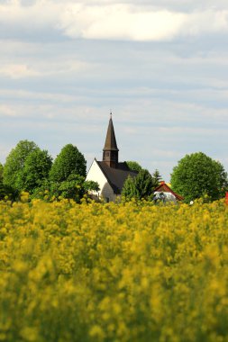 WROCLAW, POLAND - 24 Mayıs 2021: Gogolow 'daki St. Martin Kilisesi Sleza Dağı eteklerinde, çiçek açan tecavüz tarlalarıyla çevrili.