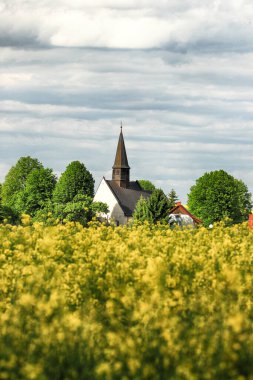 WROCLAW, POLAND - 24 Mayıs 2021: Gogolow 'daki St. Martin Kilisesi Sleza Dağı eteklerinde, çiçek açan tecavüz tarlalarıyla çevrili.