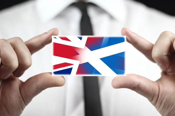 Podnikatel drží vizitku s Skotska a Velká Británie vlajka — Stock fotografie