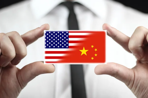 Uomo d'affari in possesso di un biglietto da visita con bandiera USA e Cina — Foto Stock