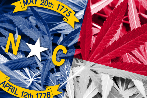 North Carolina State Flag on cannabis background. Drug policy. Legalization of marijuana
