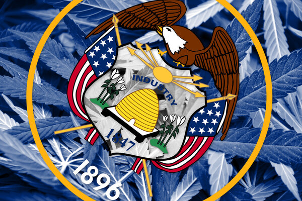 Utah State Flag on cannabis background. Drug policy. Legalization of marijuana