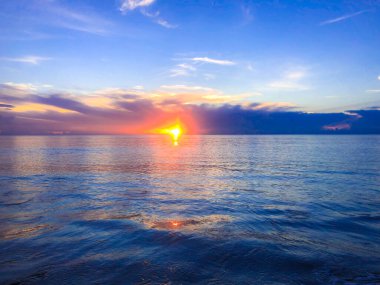 Okyanusta mavi, turuncu ve mor gün doğumu.