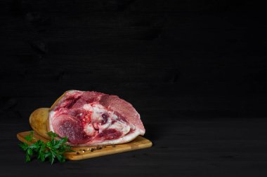 Ahşap arka planda bambudan yapılmış ahşap bir tahtanın üzerinde maydanoz ve bezelye dalıyla çiğ domuz budu yakın plan. Yemek tarifi konsepti..