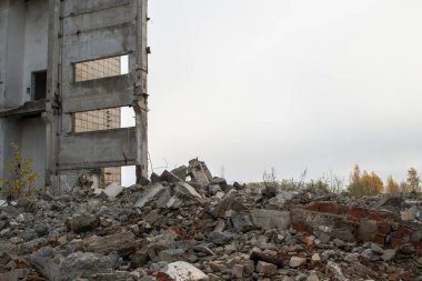 Bulanık sisli, tarafsız gri gökyüzüne karşı beton gri enkaz yığını olan harabe bir bina. Arkaplan