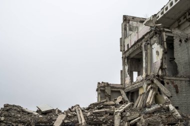 Bulanık sisli, tarafsız gri gökyüzüne karşı beton gri enkaz yığını olan harabe bir bina. Arkaplan