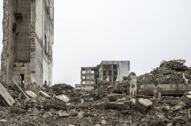 Bulanık sisli, tarafsız gri gökyüzüne karşı beton gri enkaz yığını olan harabe bir bina. Arkaplan