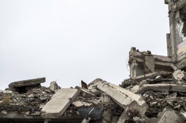 Bulanık sisli, tarafsız gri gökyüzüne karşı beton gri enkaz yığını olan harabe bir bina. Arkaplan