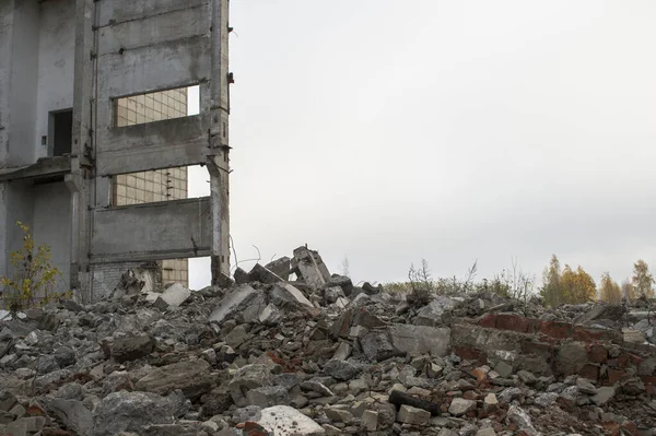 Un edificio in rovina con un mucchio di detriti grigi contro un cielo grigio neutro in una foschia nebbiosa. Contesto — Foto Stock