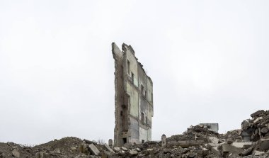 Panorama. Gri beton moloz yığınları ve çökmüş bir duvarın kalıntıları puslu bir gökyüzüne karşı..