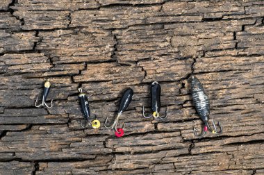 Set of lures for ice fishing shot from above on a cracked wooden background clipart