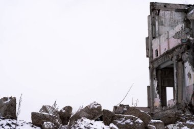 Önünde gri beton molozlar olan harabe bir binanın kalıntıları gri gökyüzüne karşı. Geçmişi. Mesaj için yer. Ön plana odaklan..