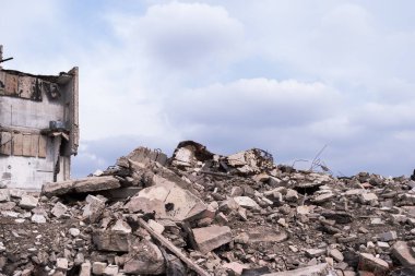 İnşaat enkazı yığını binanın arka planına ve bulutlu gri gökyüzüne çarpıyor. Arkaplan.