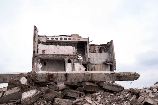 手前にコンクリートの瓦礫の山がある灰色の空に対する破壊された建物 — ストック写真