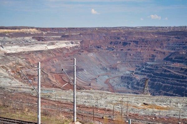 Power lines, the boom of a walking excavator against the background of an iron ore quarry and mining equipment. Background. Copy the space.