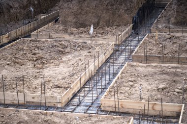 Evin inşaatı, beton temeli takviyenin kaynaklı yapısına dökme hazırlığıyla başladı. Arkaplan.