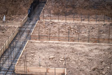 Evin inşaatı, beton temeli takviyenin kaynaklı yapısına dökme hazırlığıyla başladı. Arkaplan.