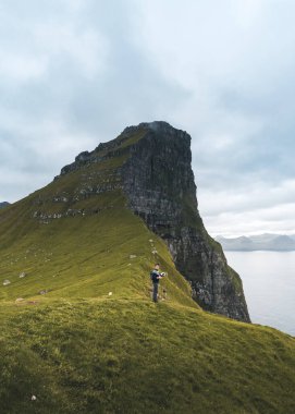 Kalsoy Island with Kallur lighthouse on on Faroe islands, Denmark, Europe. Clouds over high cliffs, turquoise Atlantic ocean and spectacular views. clipart