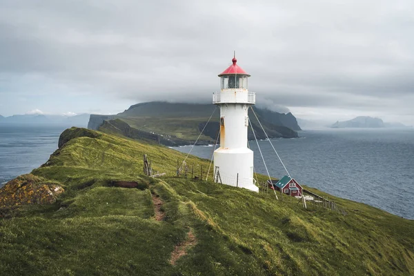 Faroe Adası 'ndaki Mykines Holmur adasındaki Deniz fenerine doğru bakın. Atlantik Okyanusu manzaralı bulutlu bir gün..