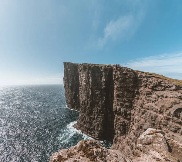 Färöarna Traelanipa slavar klippa ses stiger över havet intill sjön Sorvagsvatn. Moln och blå himmel under sommaren på ön vagar på Färöarna. — Stockfoto