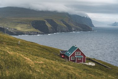 Faroe Adası 'ndaki Mykines Holmur adasındaki Deniz fenerine doğru bakın. Atlantik Okyanusu manzaralı bulutlu bir gün..