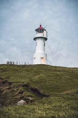 Faroe Adası 'ndaki Mykines Holmur adasındaki Deniz fenerine doğru bakın. Atlantik Okyanusu manzaralı bulutlu bir gün..