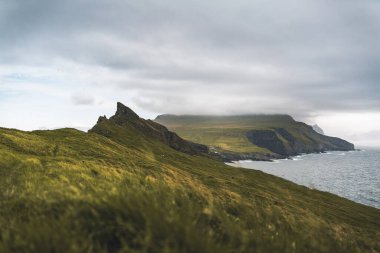 Yeşil çimen manzarası ve Atlantik Okyanusu olan güzel Mykines Adası. Mykines Adası, Faroe Adaları, Avrupa.