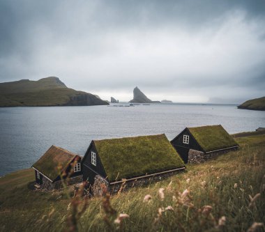 Baharda Dranganir ve Tindholmur manzaralı Bour köyünün Faroe kıyısındaki Bour köyünde otlarla kaplı resimli evler..