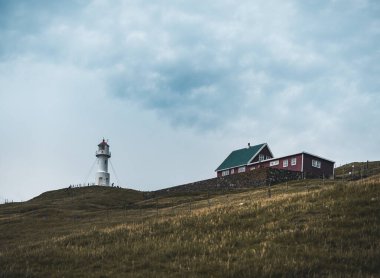 Faroe Adası 'ndaki Mykines Holmur adasındaki Deniz fenerine doğru bakın. Atlantik Okyanusu manzaralı bulutlu bir gün..