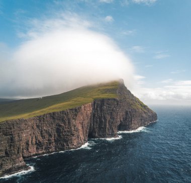 Faroe Adaları Traelanipa. Kölelerin kaya uçurumu okyanusun üzerinde Sorvagsvatn Gölü 'nün yanında yükseliyor. Faroe Adaları 'ndaki vajina adasında bulutlar ve mavi gökyüzü..
