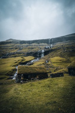 Faroe adalarındaki Saksun köyündeki şelaleler. Etrafta insan yok, geleneksel taş evler..