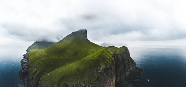 Воздушная панорама небольшого белого маяка, расположенного на краю огромной скалы и острова Калсой. Калсой - изолированный маленький остров на северо-востоке Фарерских островов. — стоковое фото