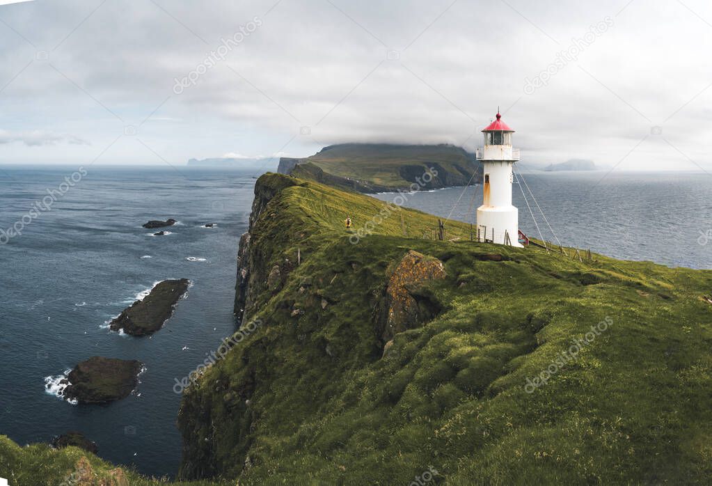View Towards Lighthouse on the island of Mykines Holmur, Faroe Islandson a cloudy day with view towards Atlantic Ocean.
