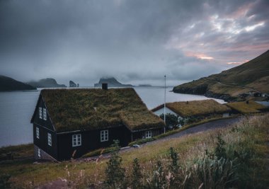 Baharda Dranganir ve Tindholmur manzaralı Bour köyünün Faroe kıyısındaki Bour köyünde otlarla kaplı resimli evler..
