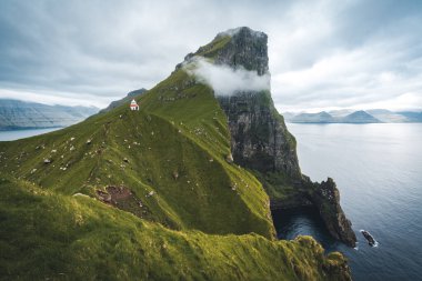 Danimarka, Avrupa 'daki Faroe adalarında Kallur deniz feneri olan Kalsoy Adası. Yüksek uçurumların üzerindeki bulutlar, turkuaz Atlantik okyanusu ve muhteşem manzaralar..