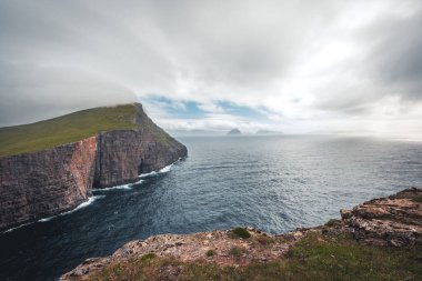 Faroe Adaları Traelanipa. Kölelerin kaya uçurumu okyanusun üzerinde Sorvagsvatn Gölü 'nün yanında yükseliyor. Faroe Adaları 'ndaki vajina adasında bulutlar ve mavi gökyüzü..