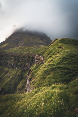 Faroe adaları, Mulafossur şelalesinden görüldüğü üzere Vagar Adası 'ndaki benim kinime doğru fırtınalı bir manzaraya sahipler. Atlantik okyanus dalgalı alçak bulutlar.