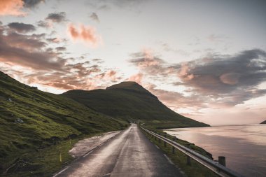 Faroe Adaları Kalsoy gün batımında... pembe gökyüzü ve kayalıklarıyla....