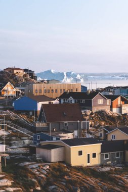 Grönland, Ilulissat 'ın Arktik şehrinin hava manzarası gün doğumunda sisle kaplandı. Kasabanın merkezinde renkli evler, yaz aylarında arka planda buzdağları, turuncu pembe ve güneşli bir günde.