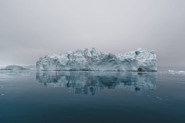 Grönland 'da buzdağlarıyla kutup manzarası gece yarısı güneş batarken ufukta güneş batıyor. Gece yarısı mevsimi boyunca sabah erken saatlerde alpenlight. Ilulissat, Batı Grönland.