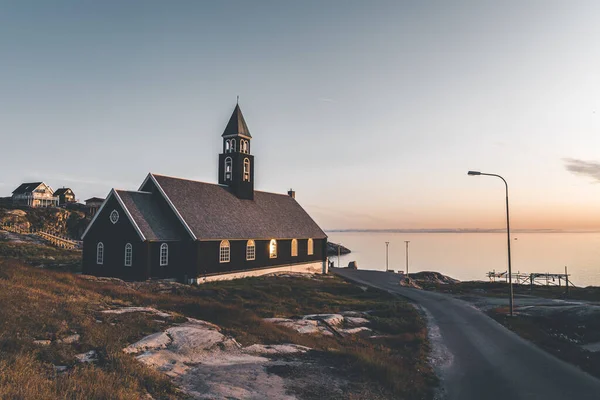 Старая деревянная Сионская церковь в арктическом городе Илулиссат, с полуночным солнечным светом и голубым небом в Северной Гренландии — стоковое фото
