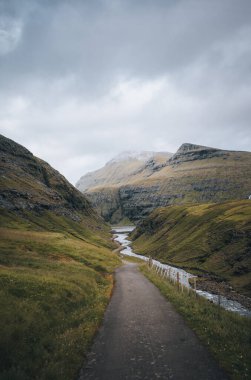Faroe Adaları 'ndaki kayalıkları, kayaları ve yüksek kayalıkları olan nehir deltası, güneşli bir bahar sabahı, Streymoy adasının Saksun köyüne yakın. Destansı İskandinav doğası.